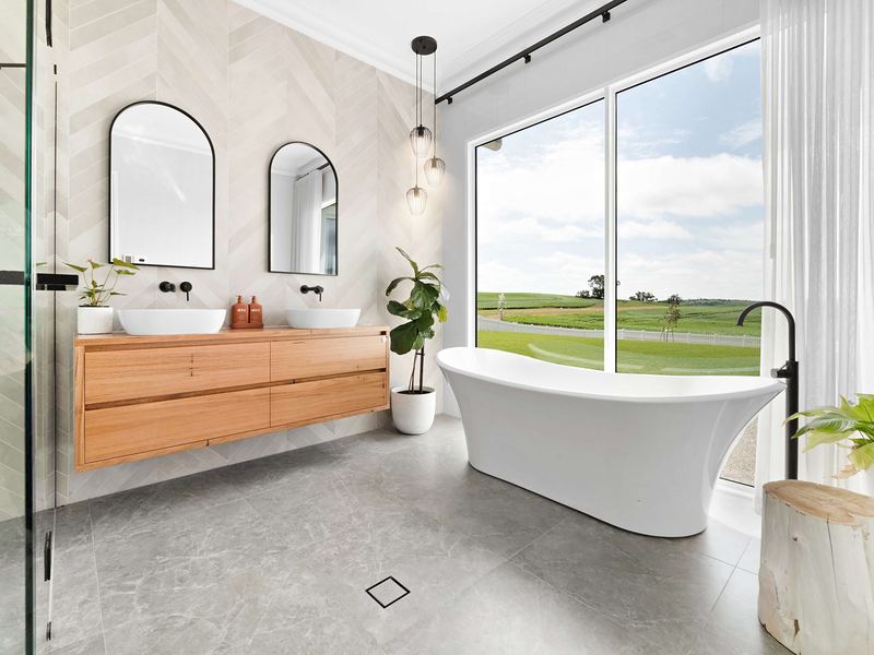 Renovated bathroom with a freestanding bath and timber vanity beside a picture window