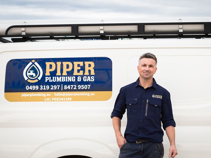 Craig beside the Piper Plumbing & Gas van with the phone numbers on the door