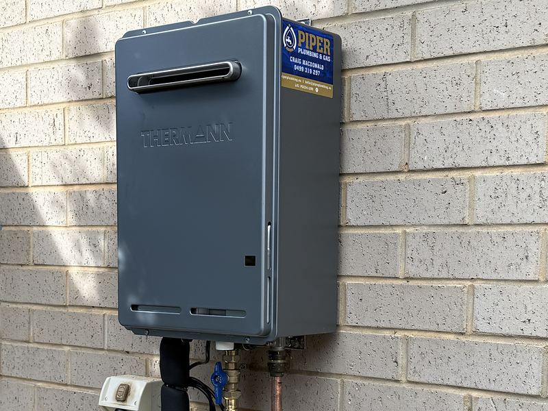 Continuous-flow gas hot water unit installed on a brick wall